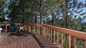 A wooden deck with a railing, surrounded by pine trees. - Pinnacle View (Truckee)