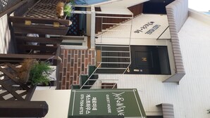 A guesthouse with a brick exterior, a wooden staircase, and a sign indicating it is a guesthouse.