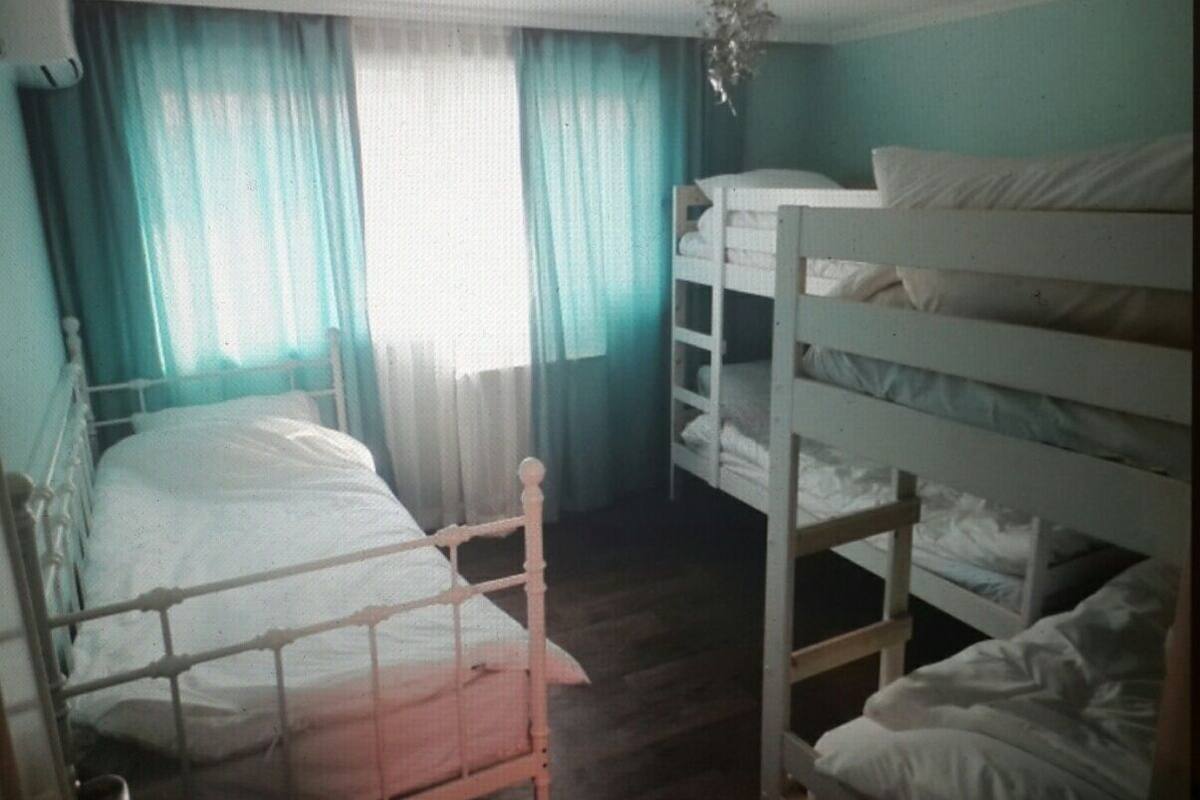 A room with bunk beds, a single bed, and curtains.