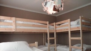 A bunk bed room with wooden bunk beds, white bedding, and a ceiling light fixture.