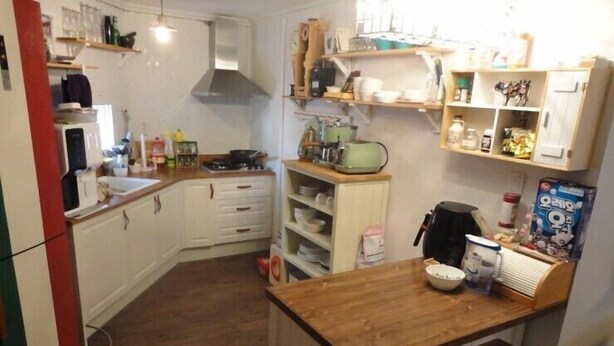 A compact kitchen with white cabinets, a wooden countertop, and a small bar area.