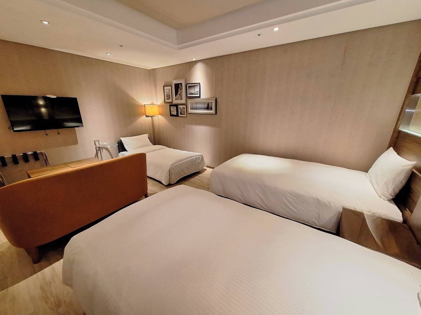 Ett hotellrum med två sängar, en soffa, en tv och en lampa.