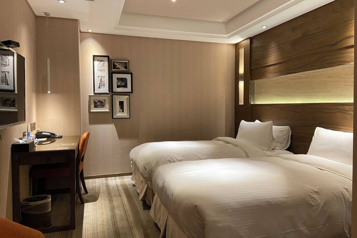A hotel room with two beds, a desk, and a chair.