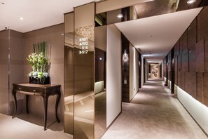 A modern hotel corridor with a wooden desk and a vase of flowers, and directional signs indicating room numbers. - Green World Taipei Station (Taipei)