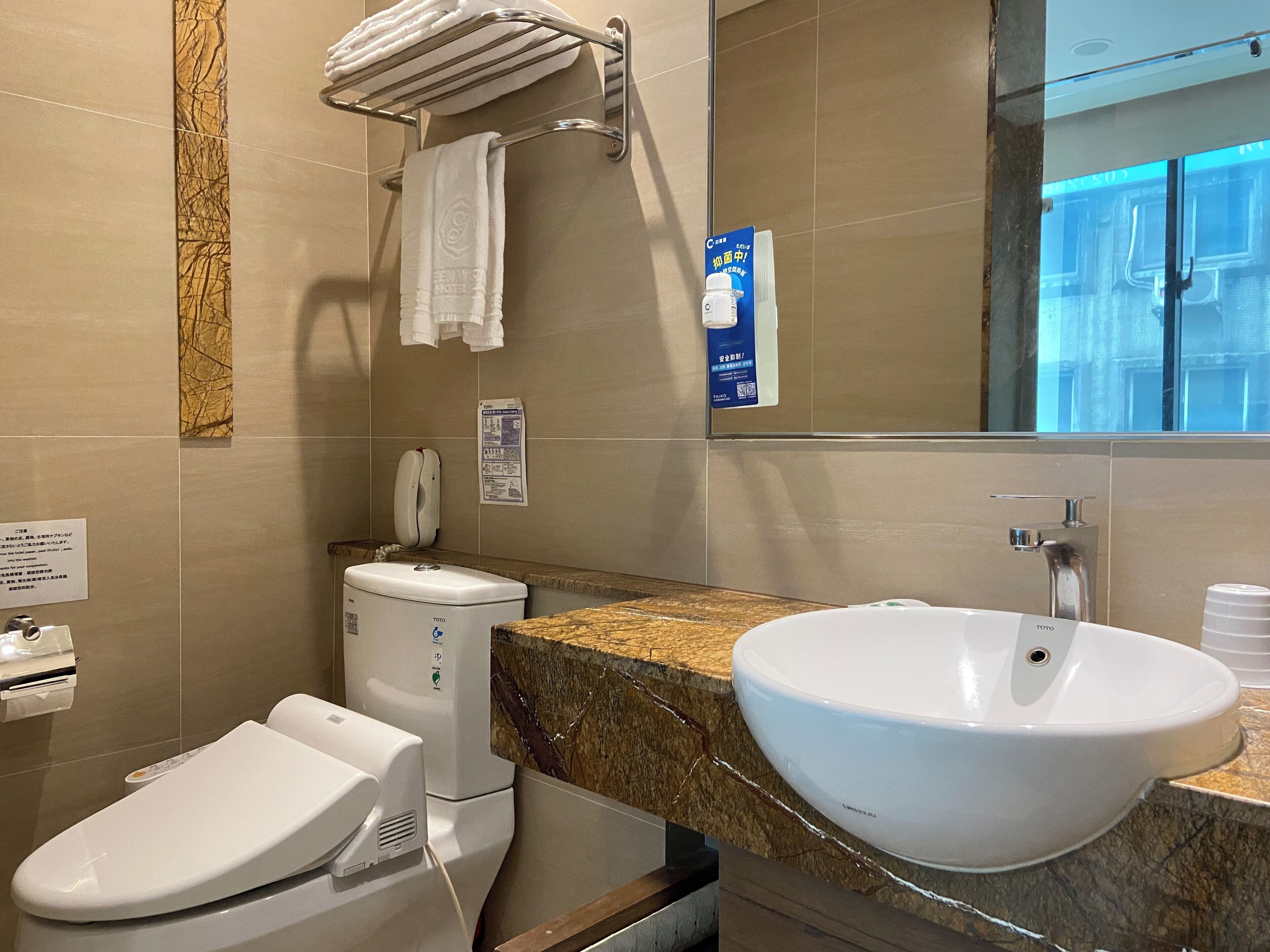 Une salle de bain moderne équipée de toilettes, d’un bidet, d’un lavabo et d’un porte-serviettes.
