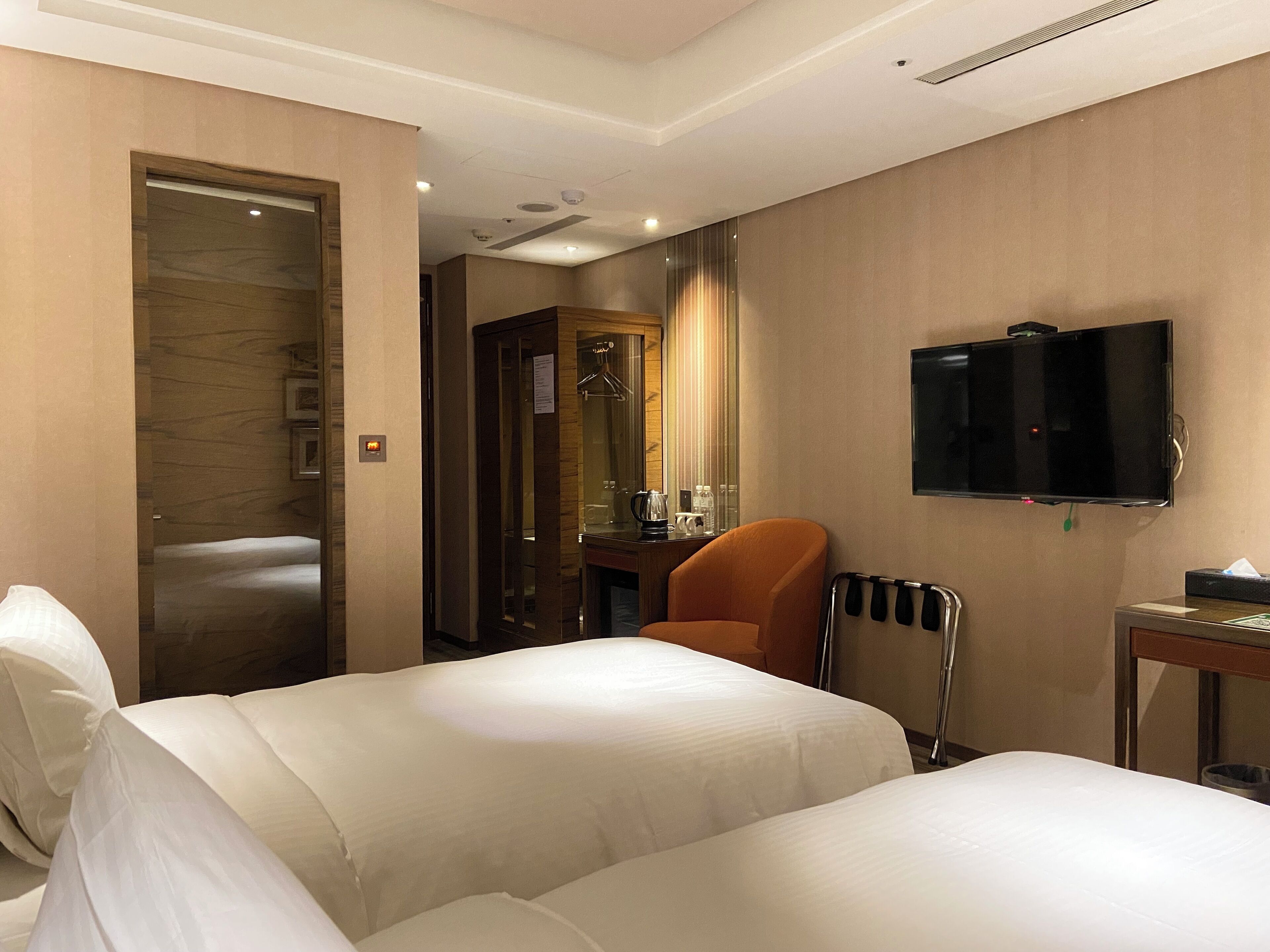 Une chambre d’hôtel avec deux lits, une télévision, une chaise et un miroir.