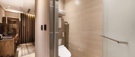 A modern bathroom with a toilet, shower, and a glass partition.