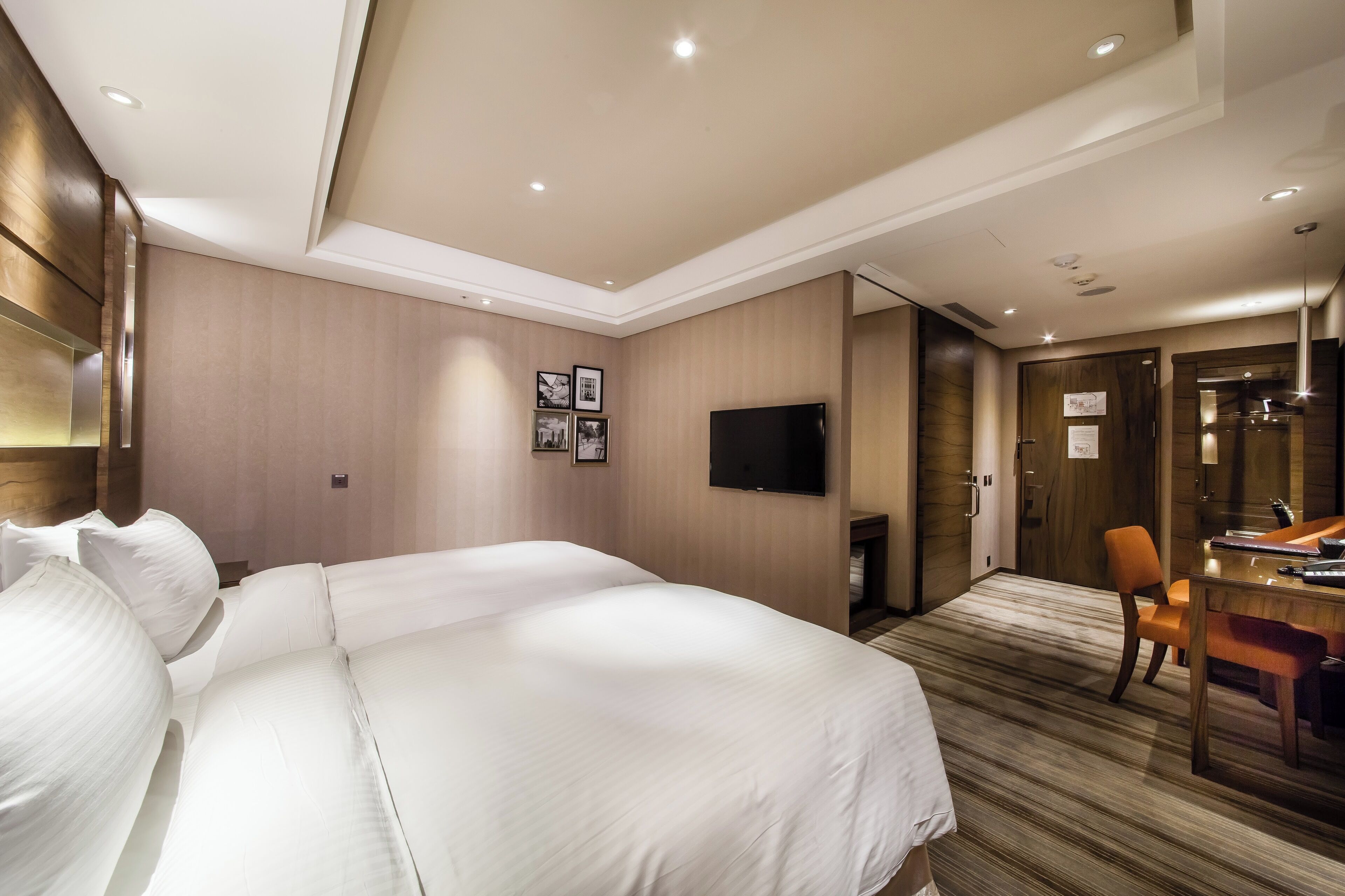 A hotel room with a large bed, a desk, and a TV.