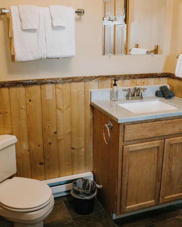 Ein Badezimmer mit einem Holzbadschränken, einem Waschbecken und einer Toilette.