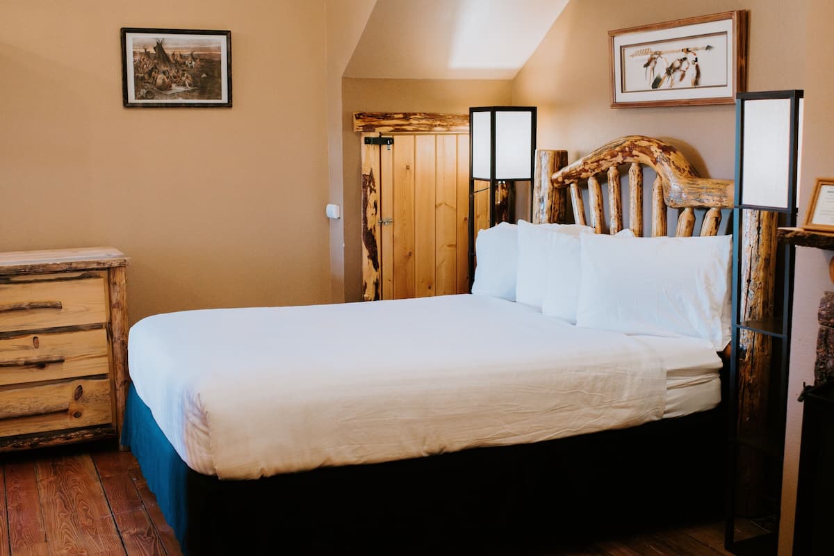 A bedroom with a wooden bed, a dresser, and a door with a rustic design.