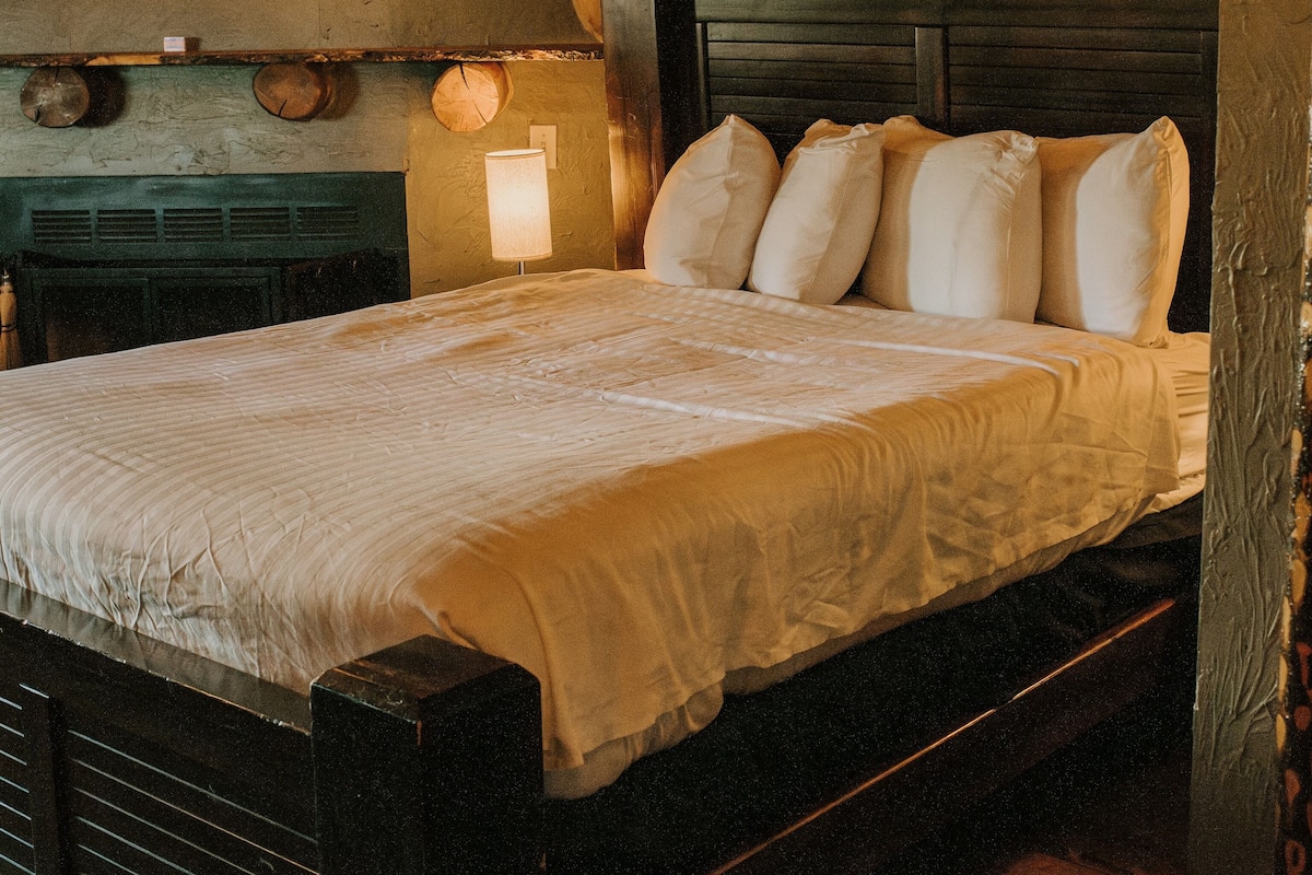 A wooden bed with a headboard, a bedside lamp, and a rustic wall decor.