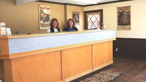 A reception desk with two staff members, wooden paneling, and posters on the walls. - City Center Motel (West Yellowstone)