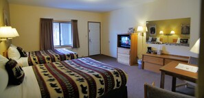 A hotel room with two beds, a TV, a desk, and a chair.