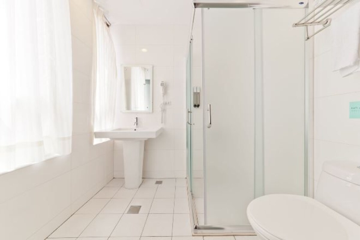 A modern bathroom with a glass-enclosed shower, a white sink, and a toilet.