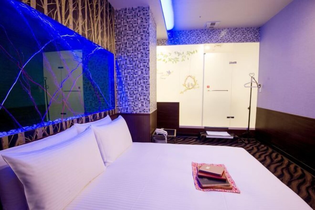 Ein Hotelzimmer mit einem Bett, einem Fenster mit Blick auf ein anderes Zimmer und einer Wand mit einem gemusterten Design.