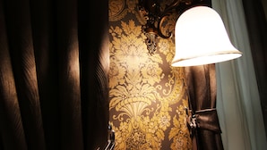 A bathroom with a decorative wall, a light fixture, and a curtain.