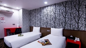 Une chambre d’hôtel avec deux lits, un bureau et une table de chevet rouge.