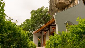 A pathway leading to a building with a stone facade, surrounded by greenery. - Mua Caves Ecolodge (Hoa Lu)