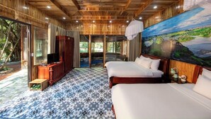 A room with wooden paneling, two beds, a television, and a large window overlooking a scenic landscape. - Mua Caves Ecolodge (Hoa Lu)