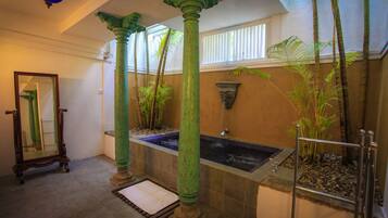 Bathroom features a bathtub, mirror, bench, and decorative lighting.