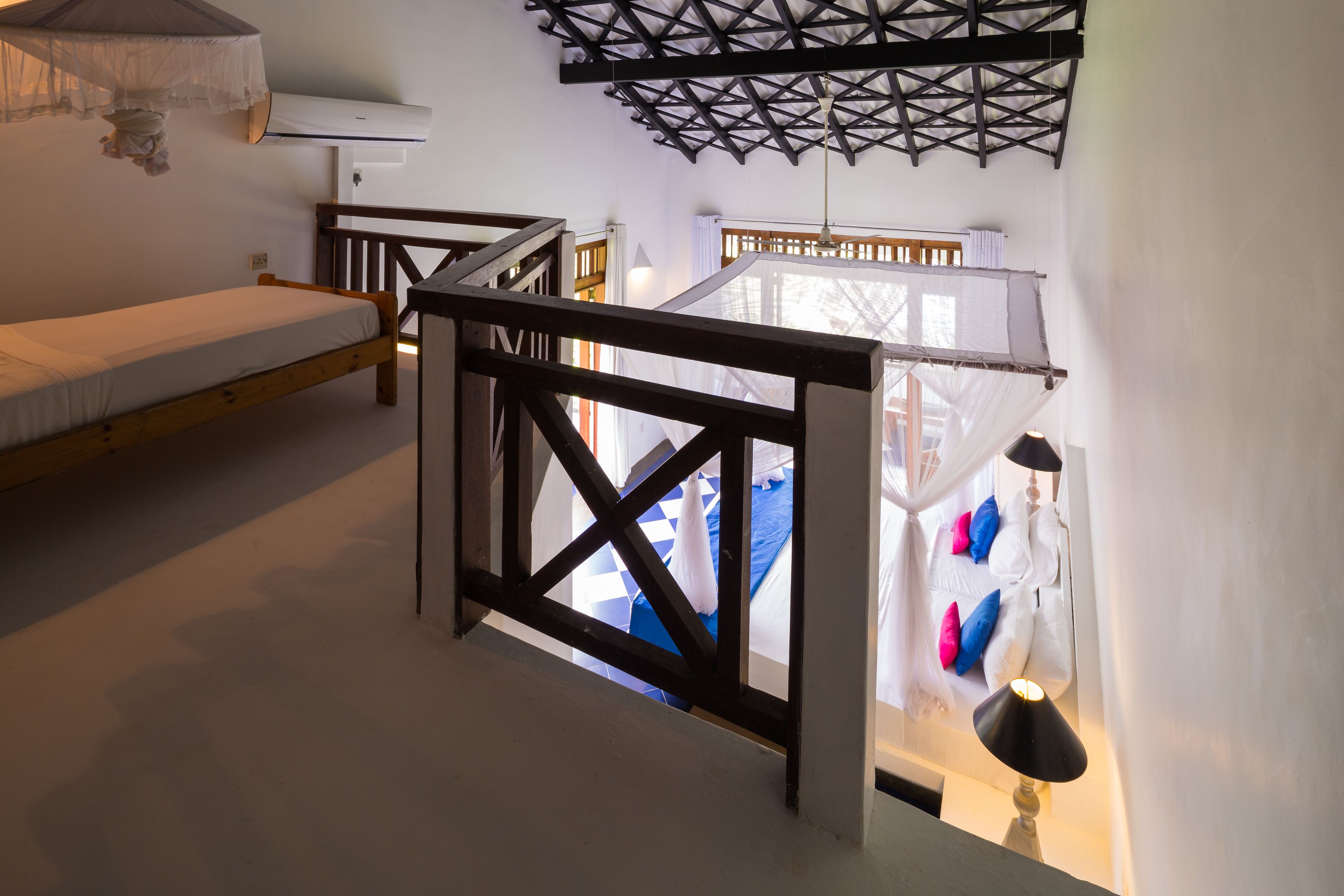 A bedroom with a wooden bed, a balcony with a view, and a ceiling fan.