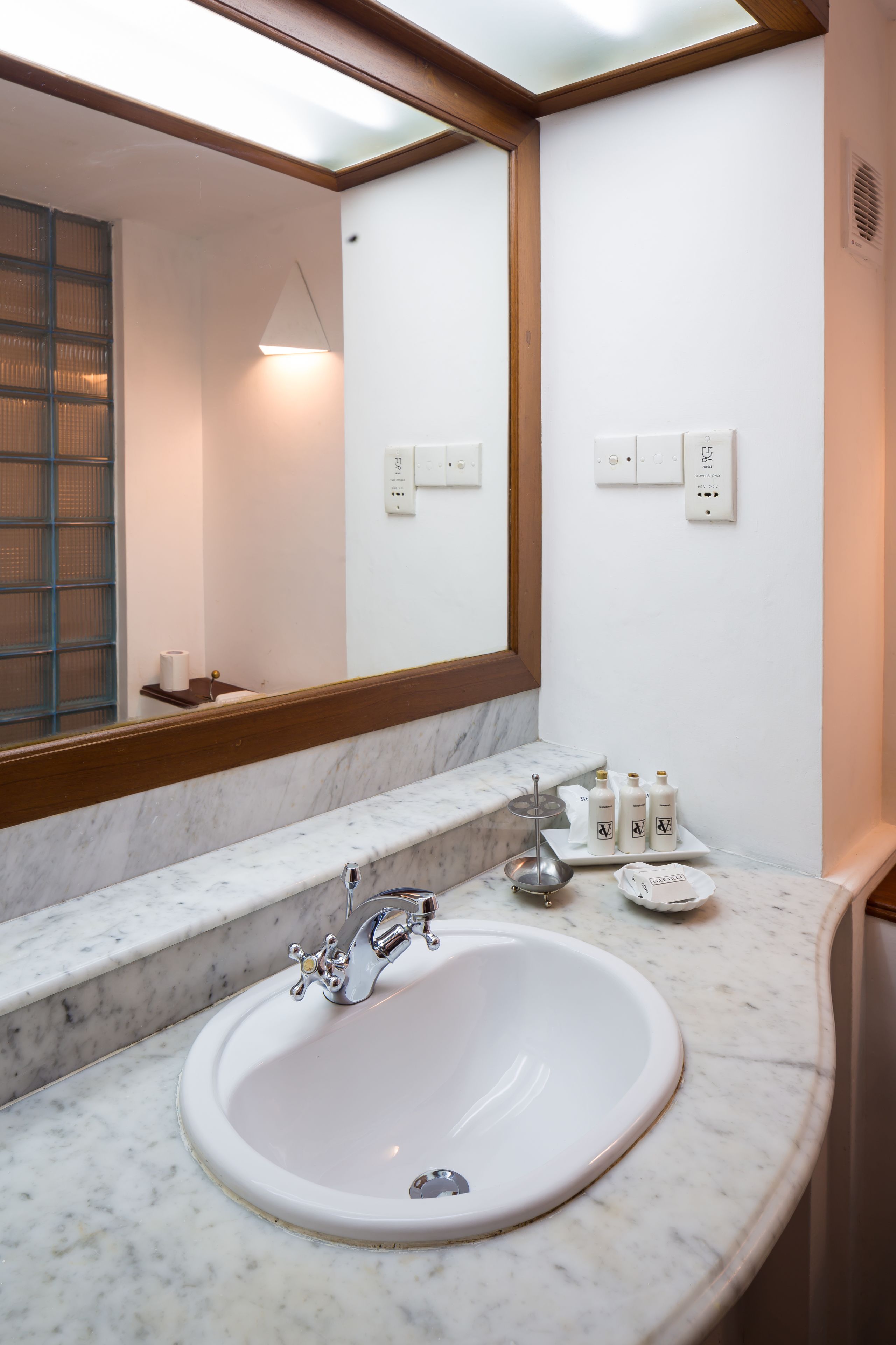 Un baño con lavamanos blanco, un espejo grande y encimera de mármol.