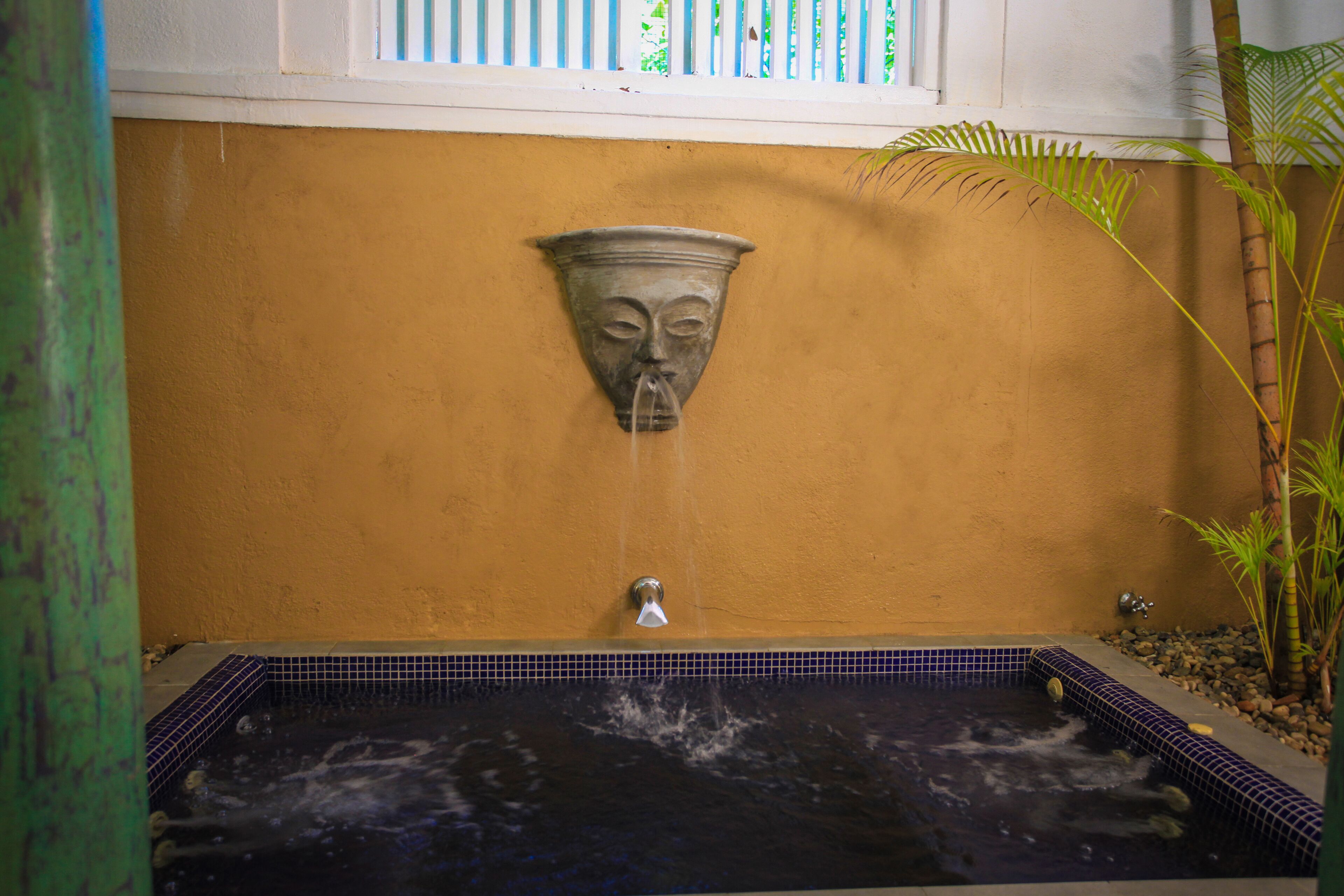 A spa area with a stone wall, a water feature, and a tiled floor.