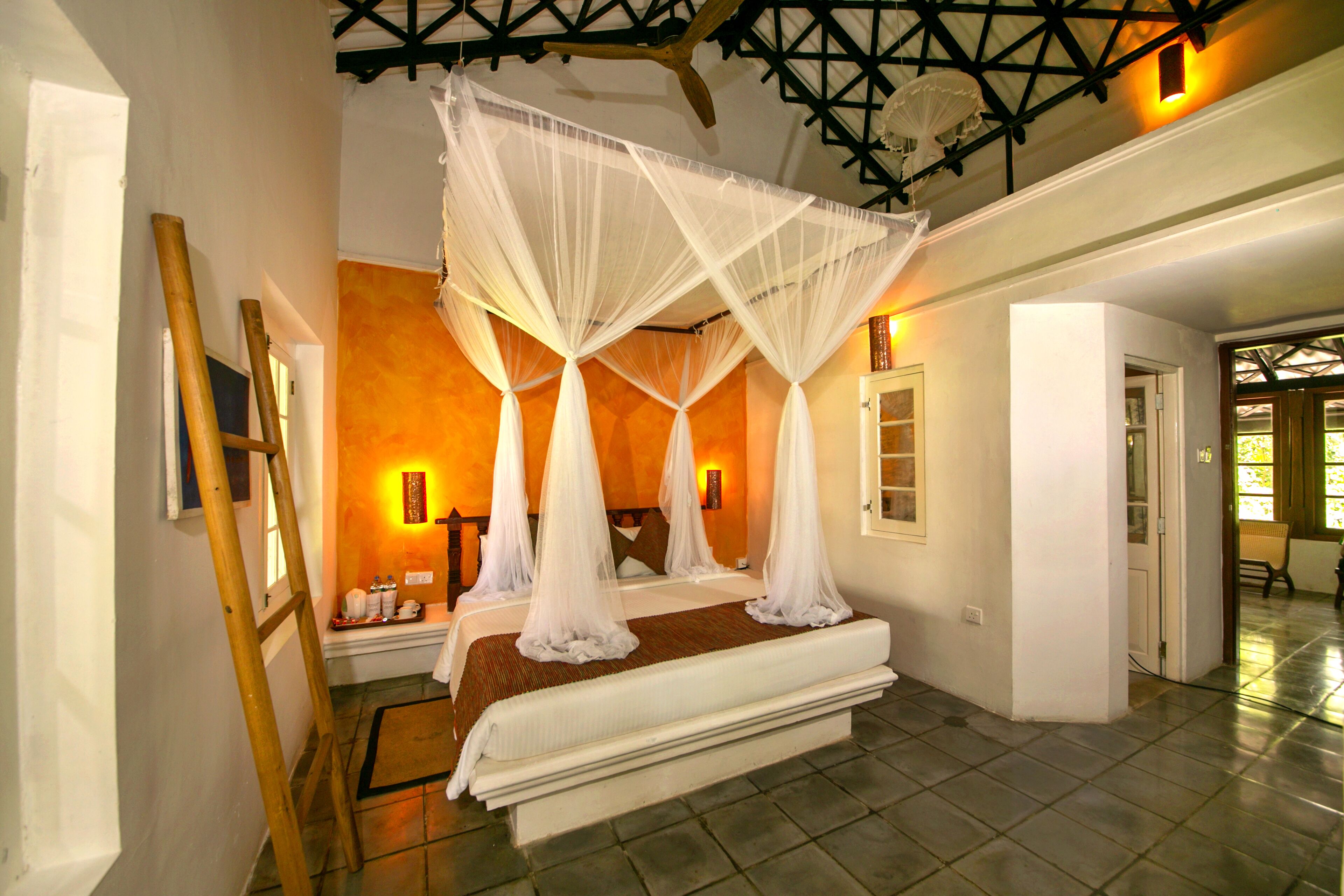A bedroom with a four-poster canopy bed, a wooden ladder, and a tiled floor.