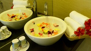 Two sinks with flower petals in water, a towel rack with towels, and a basket with towels and flowers. - Bamboo Garden Homestay (Da Nang)