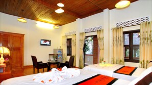 A hotel room with two beds, a desk with a chair, a television, and a window with curtains. - Bamboo Garden Homestay (Da Nang)