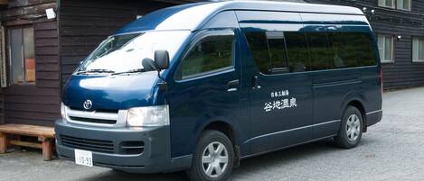 A blue van parked in front of a building with Japanese text on the side.
