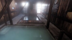 A wooden interior with a central pool, wooden walls, and a sloped ceiling. - Yachi Onsen Spa (Towada)