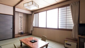 A traditional Japanese room with tatami flooring, a wooden table with a tea set, a sliding door, a large window with shoji screens, and a television on a cabinet. - Yachi Onsen Spa (Towada)