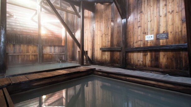 A traditional wooden bathhouse with a hot spring, wooden walls, and a sign indicating the room number. - Yachi Onsen Spa (Towada)