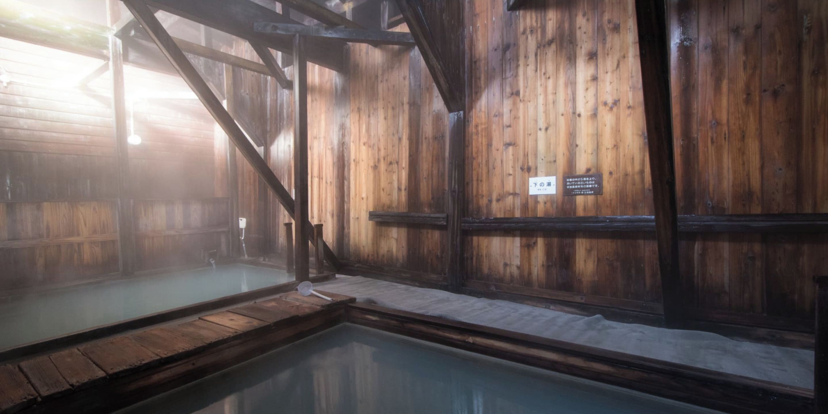 A traditional wooden bathhouse with a wooden floor and a small pool.