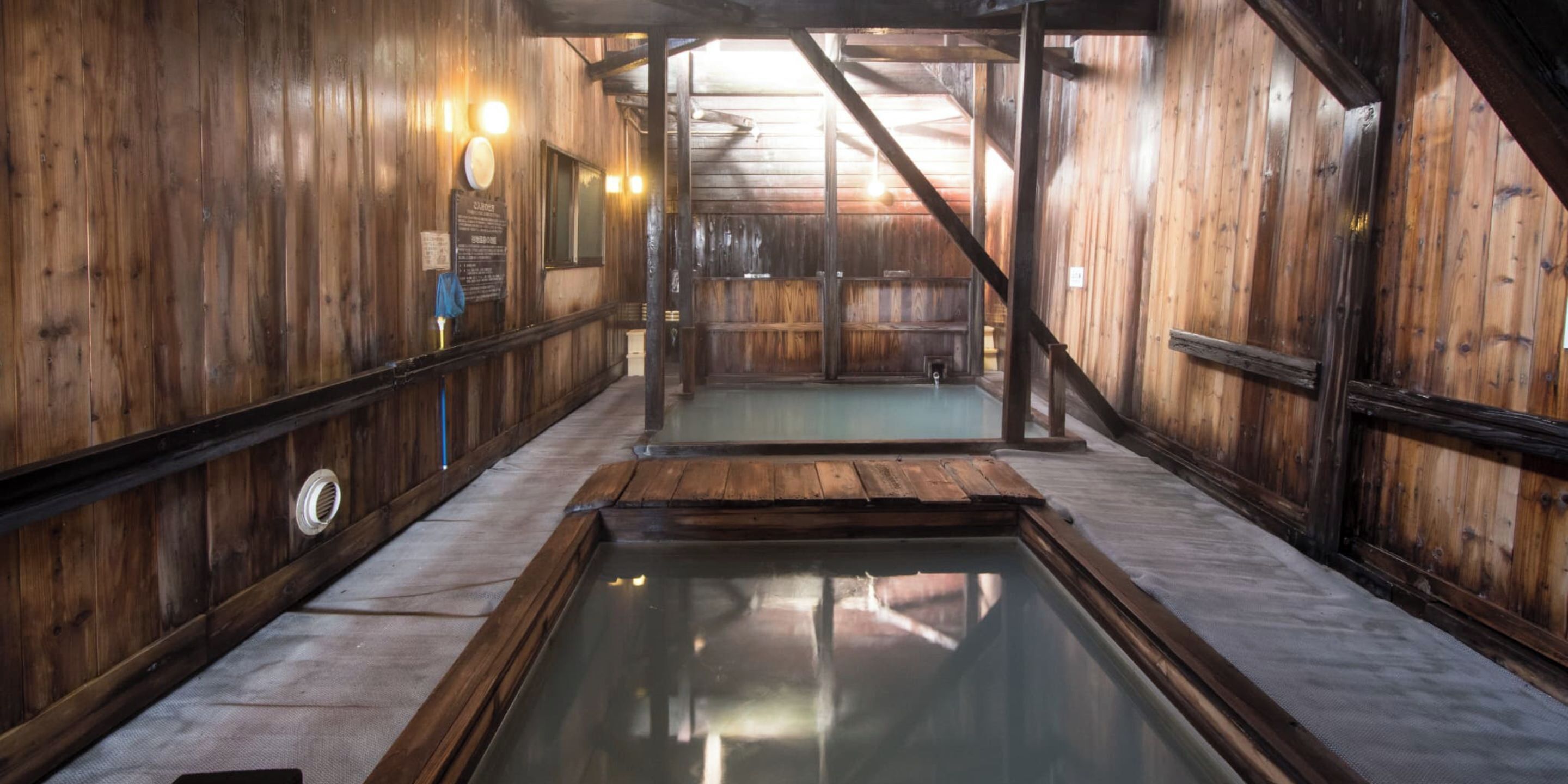 A wooden interior with a central pool, wooden walls, and a sloped ceiling.