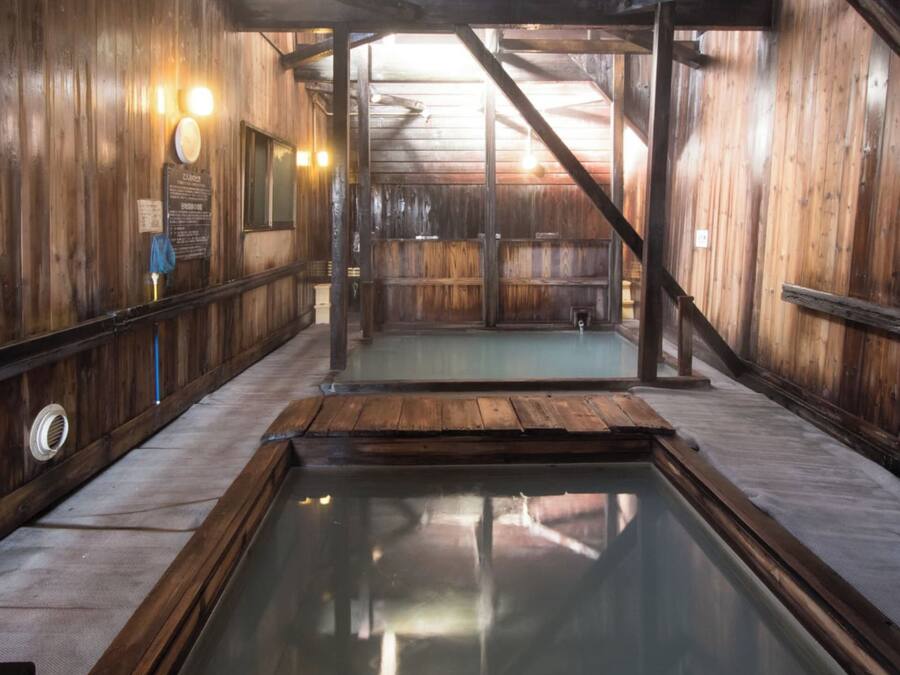 A wooden interior with a central pool, wooden walls, and a sloped ceiling.