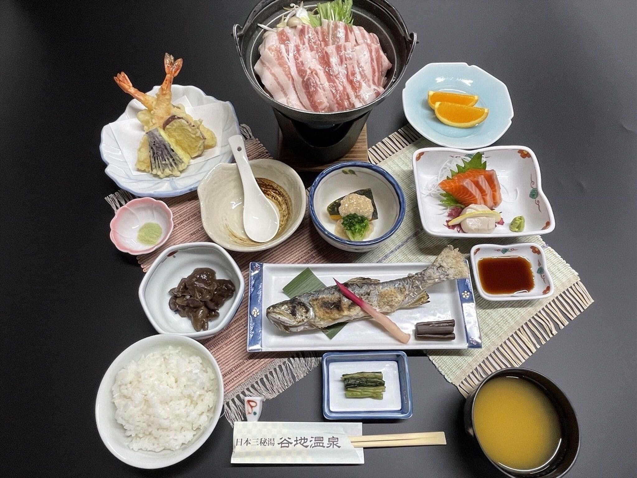 A variety of Japanese dishes including sushi, sashimi, and rice, arranged on a table.