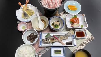 A variety of Japanese dishes including sushi, sashimi, and rice, arranged on a table.