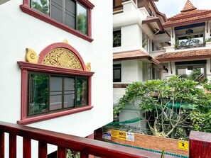 A building with a red and white facade, a decorative arch above the windows, and a balcony with a red railing.