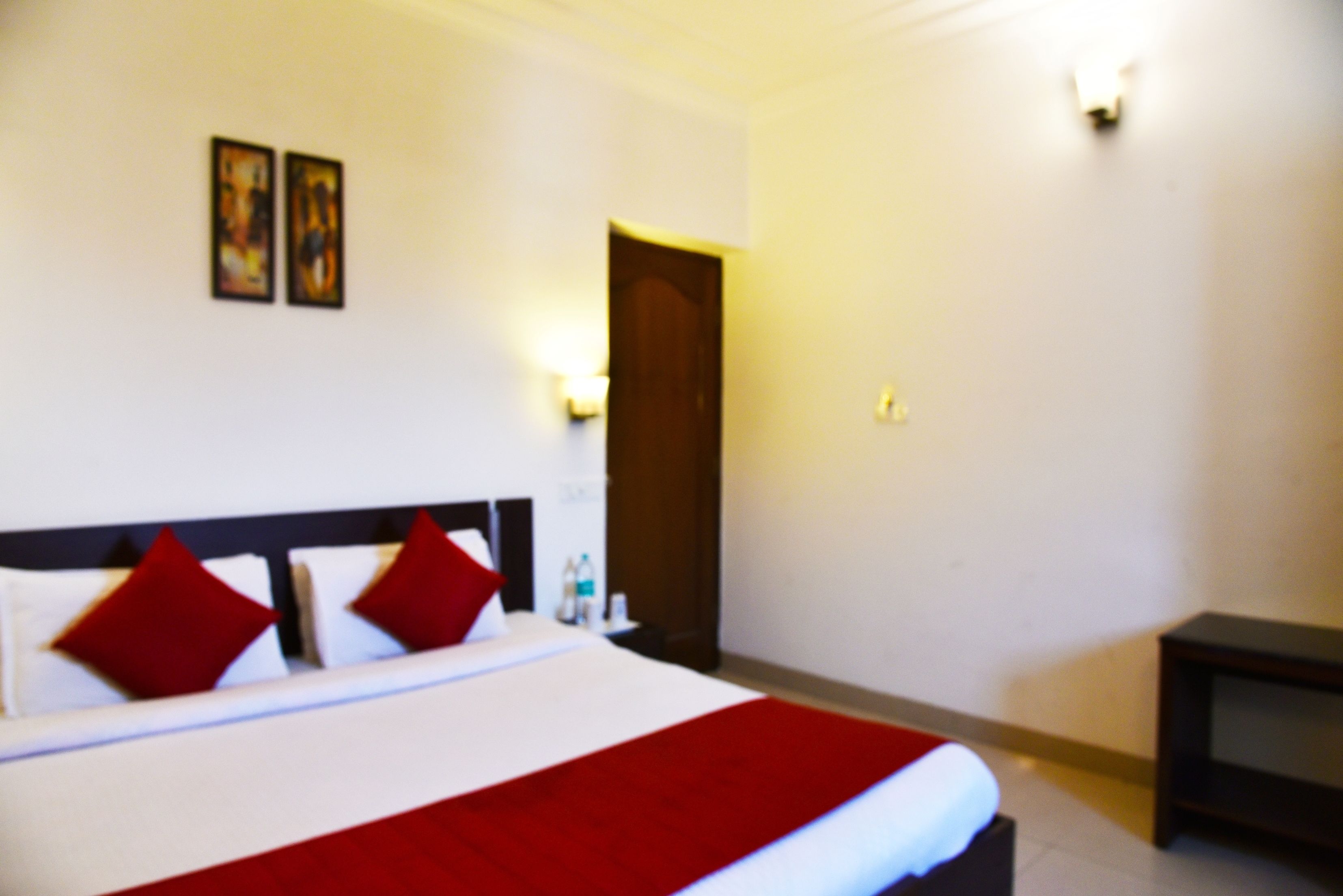 Quarto de hotel com cama, mesa de cabeceira e porta.