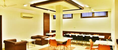 A dining area with tables and chairs, a ceiling fan, and an air conditioning unit.