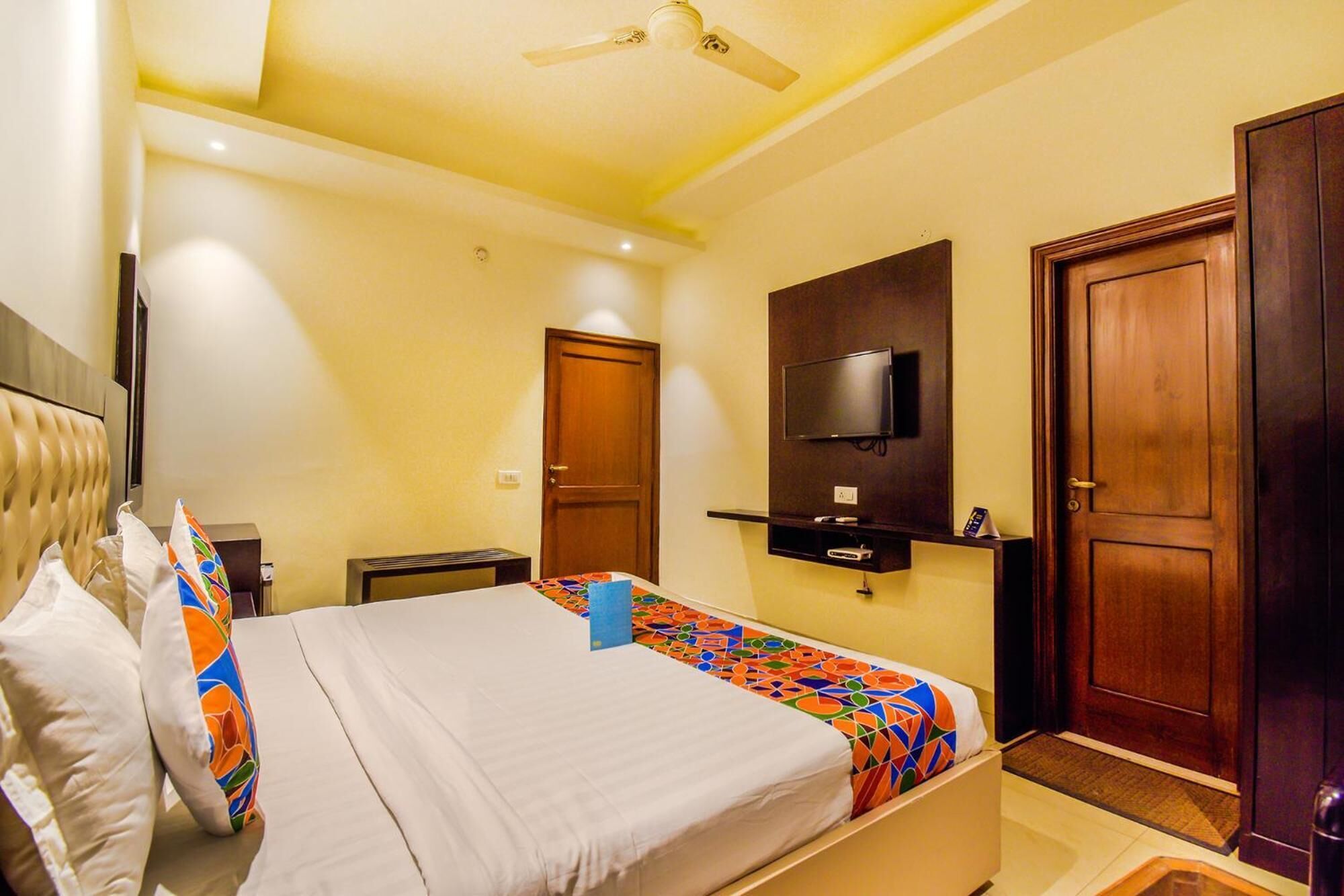 Una habitación de hotel con una cama, un televisor montado en la pared y una puerta de madera.