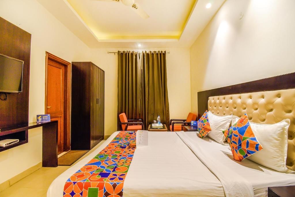 A hotel room with a large bed, a TV, a desk, and a chair.