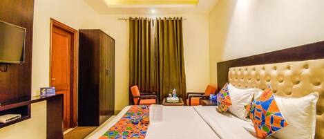 A hotel room with a large bed, a TV, a desk, and a chair.