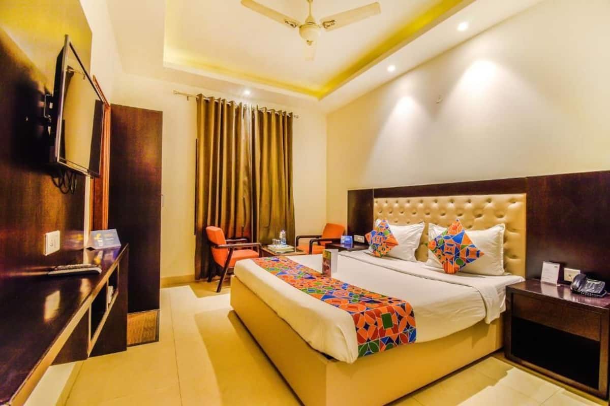A hotel room with a large bed, a desk with a TV, and a chair.