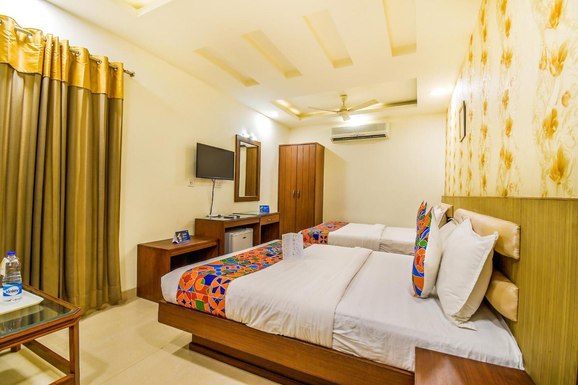 A hotel room with a bed, a desk, a wardrobe, a TV, and a ceiling fan.