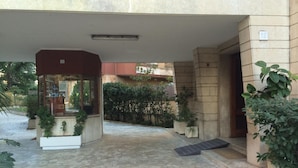 Un patio empedrado con entrada de puerta de cristal, plantas en macetas y el número '12' visible.