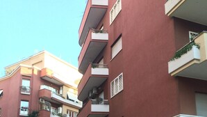 Un edificio residencial de varios pisos con balcones, una entrada porticada y un letrero que indica el número de unidad 12.