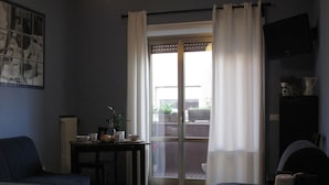 Una habitación con dos camas, una mesa con una planta y vistas al exterior a través de un ventanal.